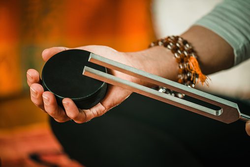 Person holding a black circular object with metallic rods.