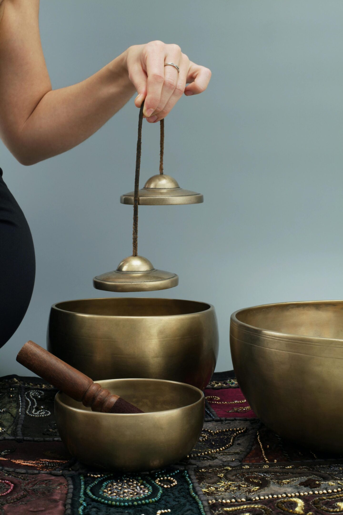 Person holding Tibetan singing bowls used for meditation.