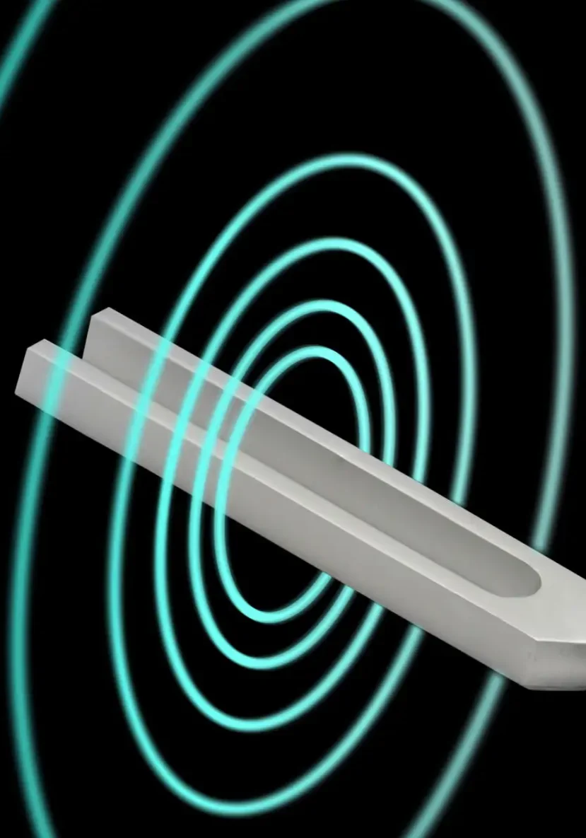 A metallic tuning fork emitting circular sound waves against a black background.
